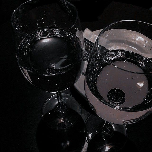 two wine glasses sitting on top of a table next to each other with water in them