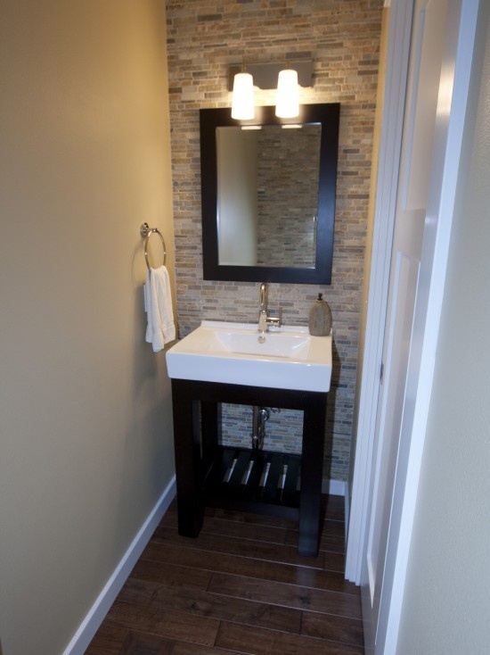 a white sink sitting under a bathroom mirror next to a wooden cabinet and light fixture