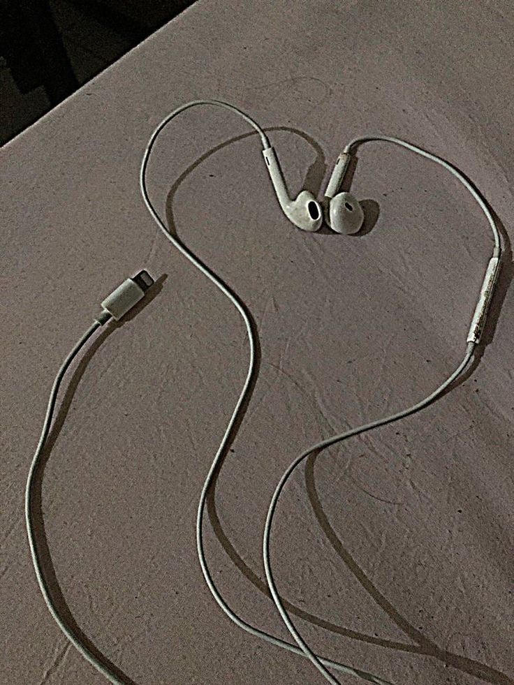 an earbud laying on top of a bed next to a pair of headphones