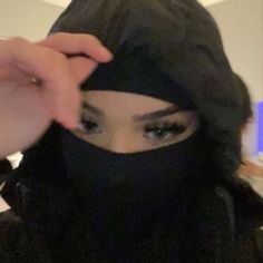 a woman wearing a hijab and covering her face with a black head scarf