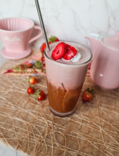 there is a drink with strawberries in it on the table