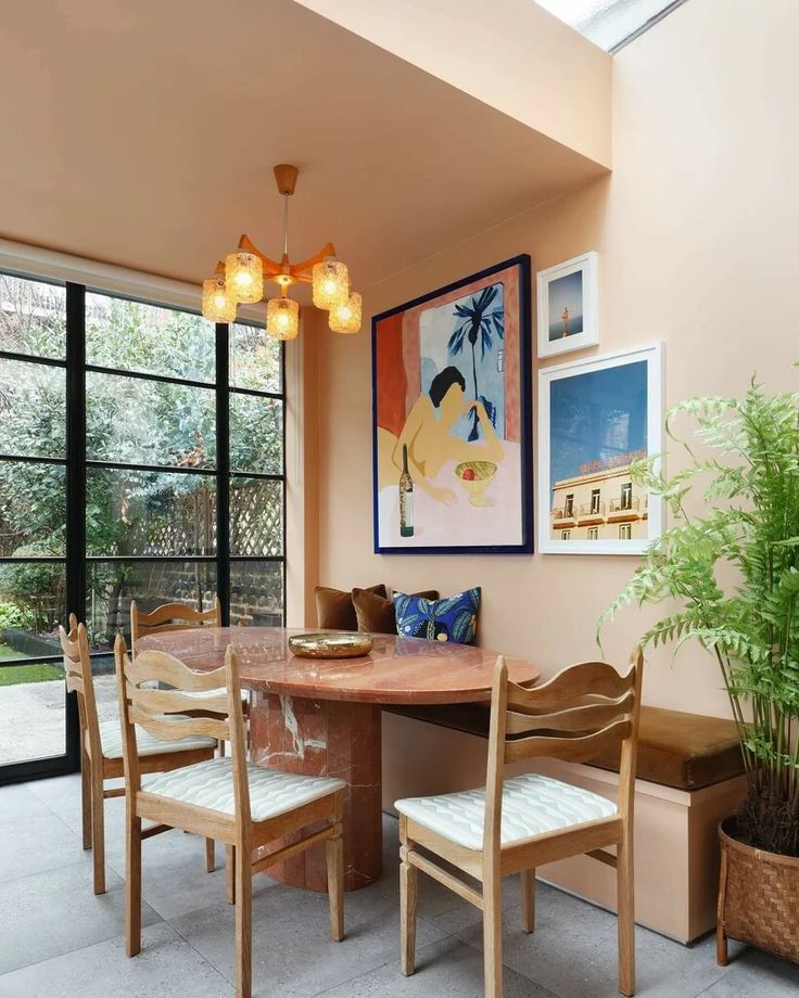 a dining room table with four chairs and a potted plant in the corner next to it