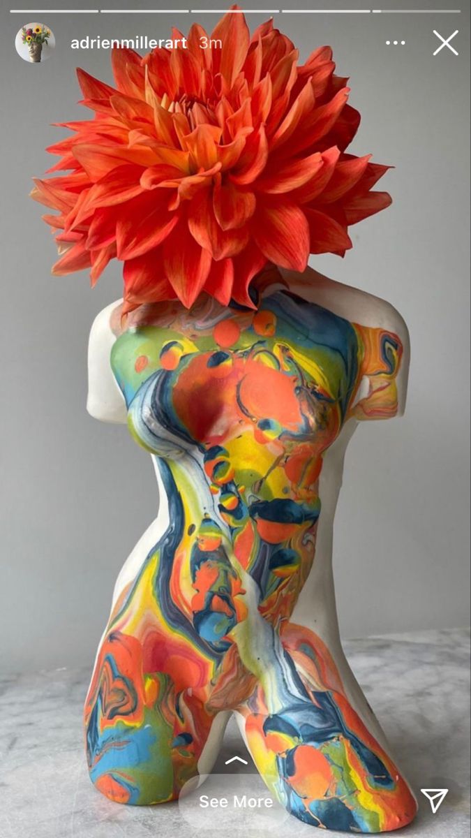 an orange flower sitting on top of a white mannequin