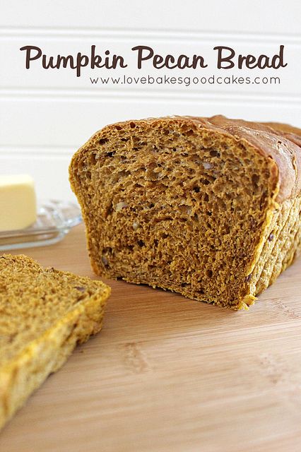 a loaf of pumpkin pecan bread sitting on top of a cutting board next to butter