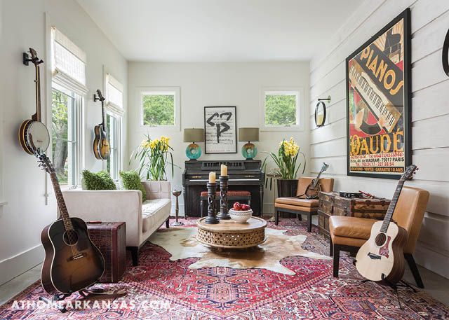 a living room filled with furniture and lots of guitars hanging on the wall next to a piano