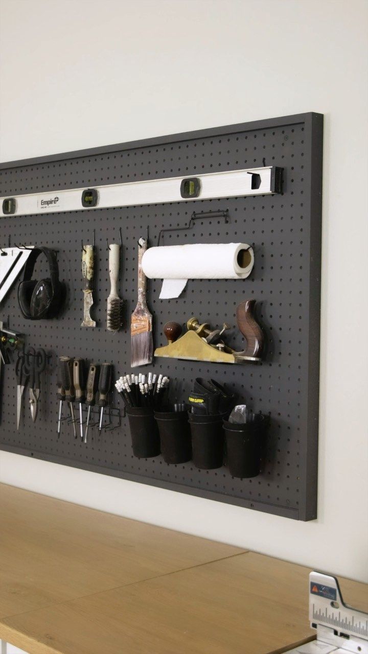 a wall mounted tool rack with various tools on it and pegs attached to the wall