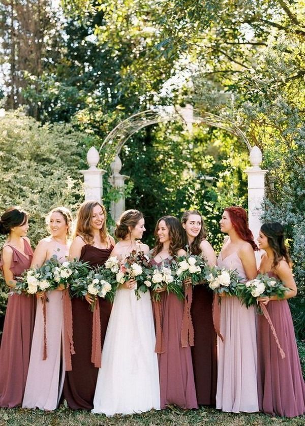 a group of women standing next to each other wearing dresses and holding bouquets in their hands