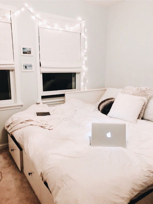 a laptop computer sitting on top of a bed in a room with white sheets and pillows