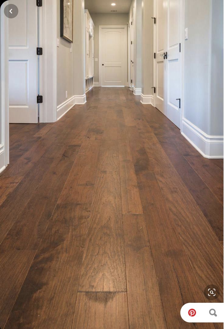 an empty hallway with wood flooring and white trim on the walls is pictured in this image