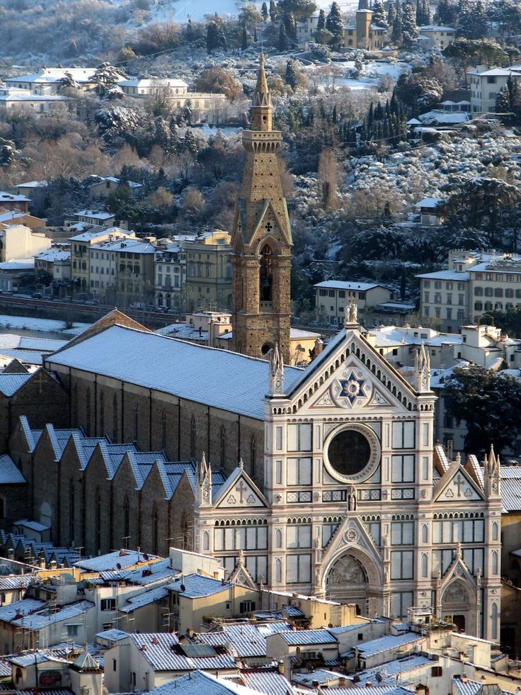 an aerial view of a church in the city with snow on the ground and buildings around it