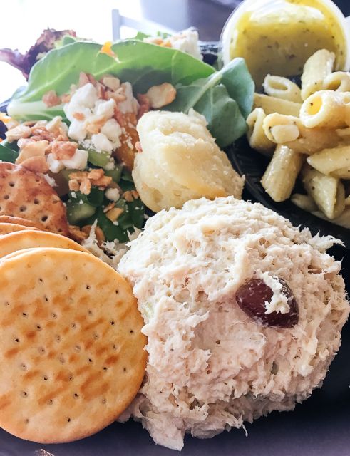 a close up of a plate of food with crackers, salad and other items