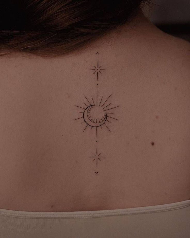 the back of a woman's neck with a sun and stars tattoo on it