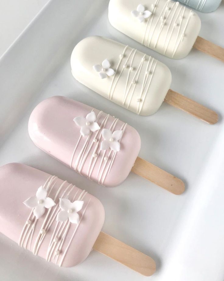 four popsicles with flowers on them sitting in a white tray next to each other