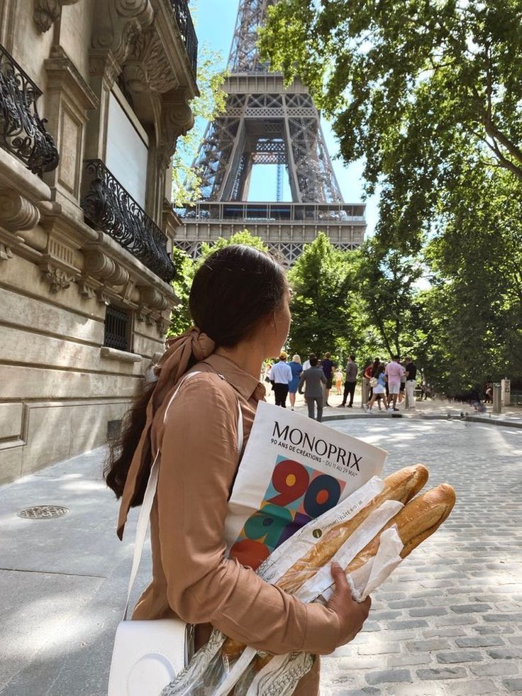 a woman reading a book in front of the eiffel tower