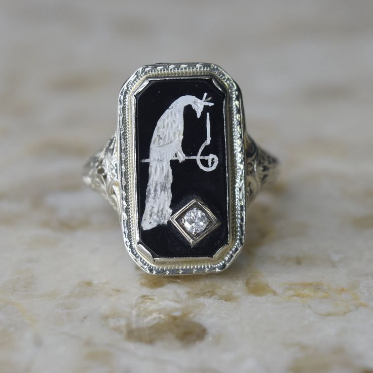 Antique Art Deco ring made of filigreed white gold. The ring is set with black onyx enameled with a peacock. There is a .10 diamond in the corner. Era: Art Deco Markings: None  Material: 14k gold (acid tested) , black onyx, diamond (approx .10ct) Ring Size: 8.5 (comes with one resizing by our jeweler)  Condition: Excellent antique condition with minor surface wear from age  Shipping is free in the United States  Follow on Instagram @LUXXORVintage Art Deco Enamel Rings For Formal Occasions, White Gold Diamond Jewelry With Black Enamel, Elegant Silver Enamel Ring With Black Details, Elegant White Gold Enamel Rings, Art Deco Enamel Ring Jewelry, Enamel Jewelry With Diamond Accents For Anniversary, Art Deco Enamel Jewelry Ring, Anniversary Jewelry With Diamond Accents And Enamel, Fine Jewelry Black Enamel Diamond Ring