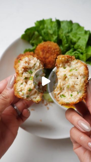 two hands holding food on a plate with lettuce and meatballs in it