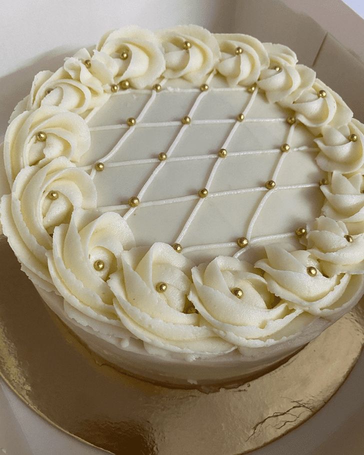 a white cake sitting on top of a table next to a gold foiled plate