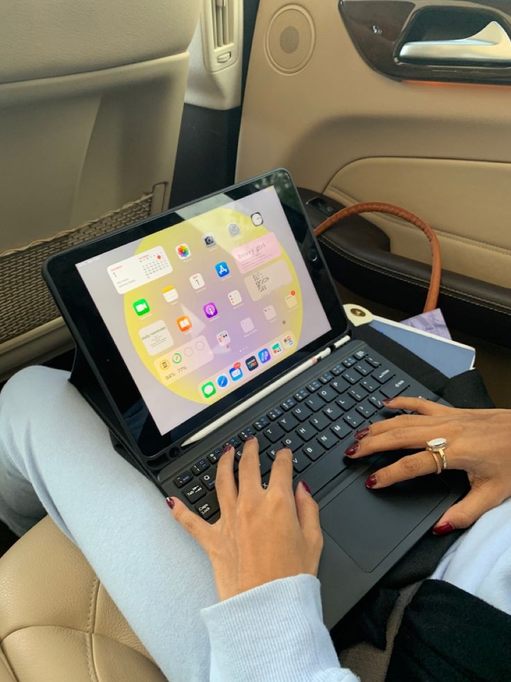 a woman sitting in the back seat of a car with her laptop computer on her lap