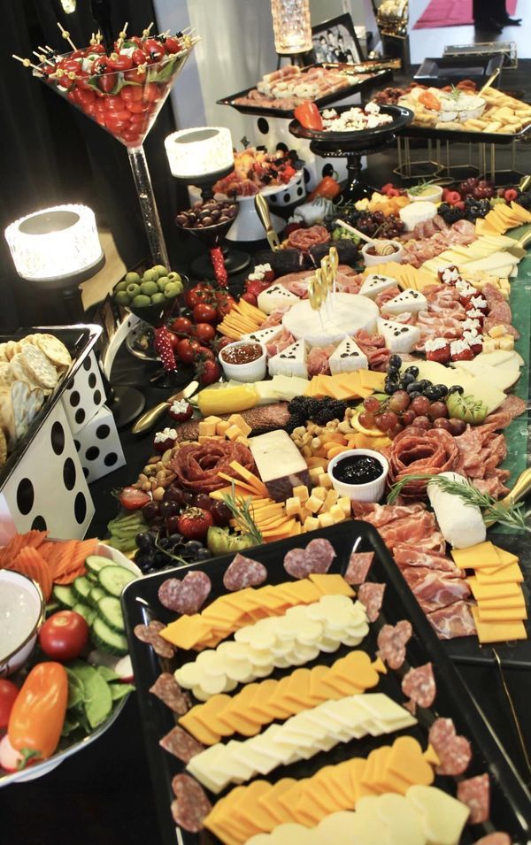 a buffet table filled with lots of different types of cheeses, meats and vegetables