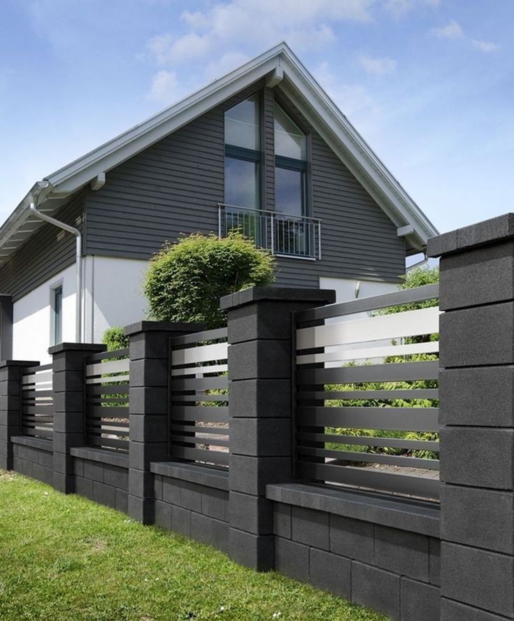 a house with a fence in front of it and grass on the ground next to it