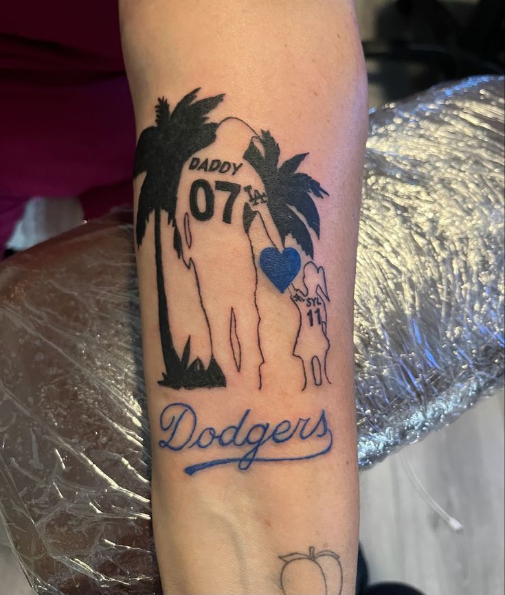 a man with a tattoo on his arm that says daddy 70th dodger and palm trees