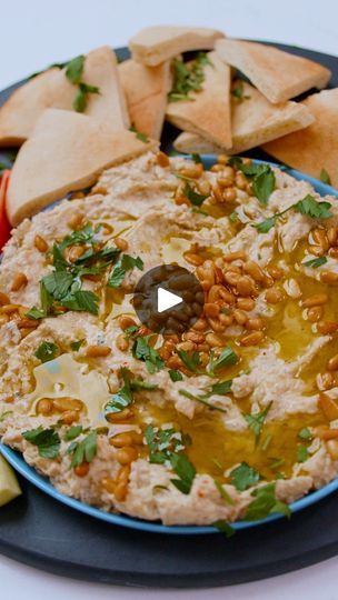 hummus and pita chips on a blue plate with an olive garnish