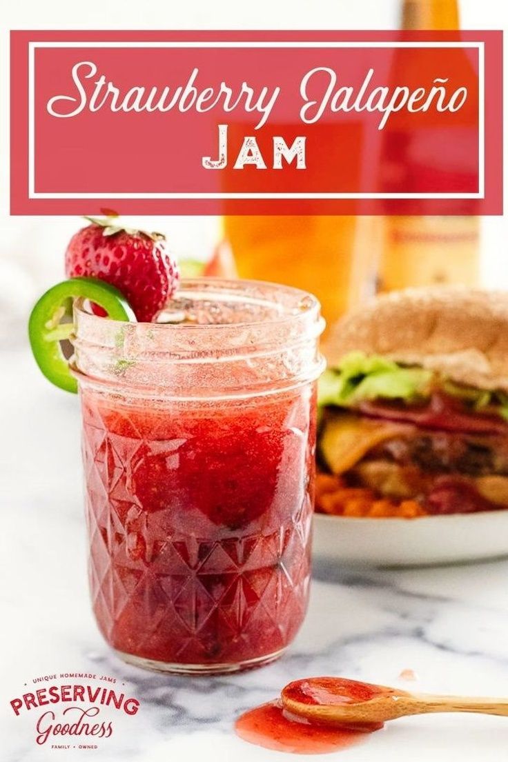 a jar filled with strawberry jam next to a plate of food