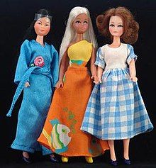 three dolls standing next to each other in front of a black background and one is wearing a blue dress