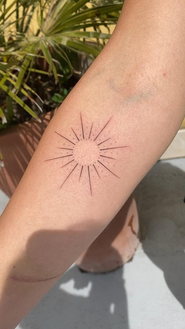 a woman's arm with a small sun tattoo on it