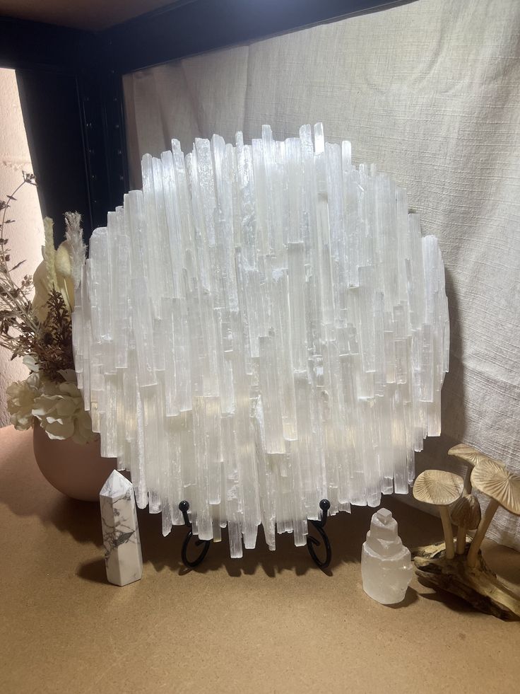 a vase filled with lots of white frosted items next to a wall mounted mirror