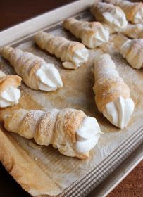 several pastries on a baking sheet with icing and powdered sugar in them