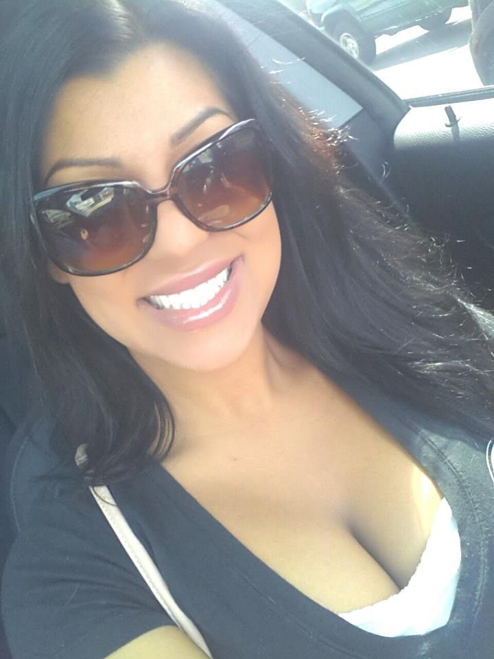 a woman wearing sunglasses sitting in the back seat of a car smiling at the camera