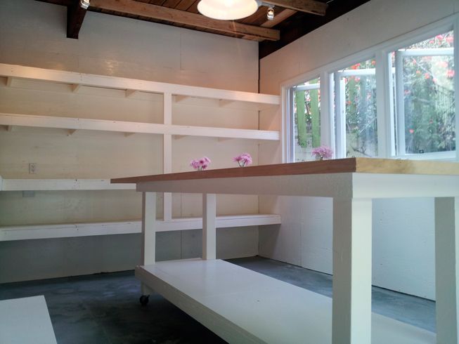 an empty room with white shelves and flowers on the counter top in front of a large window