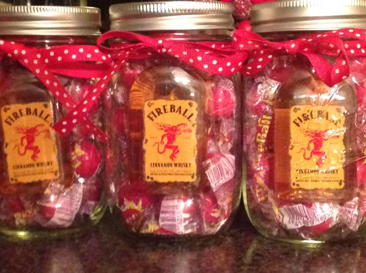 three jars filled with candy sitting on top of a counter next to a red ribbon