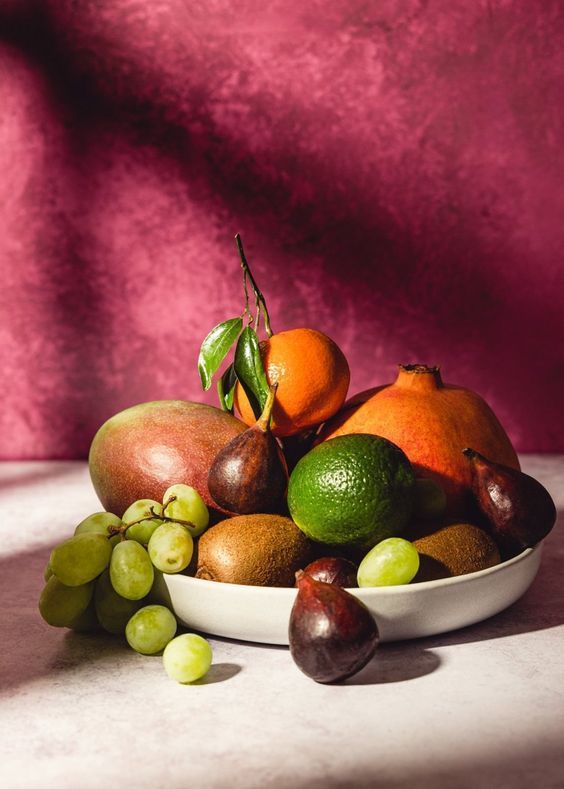 a white bowl filled with assorted fruit on top of a table