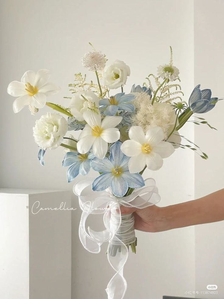 a person holding a bouquet of white and blue flowers