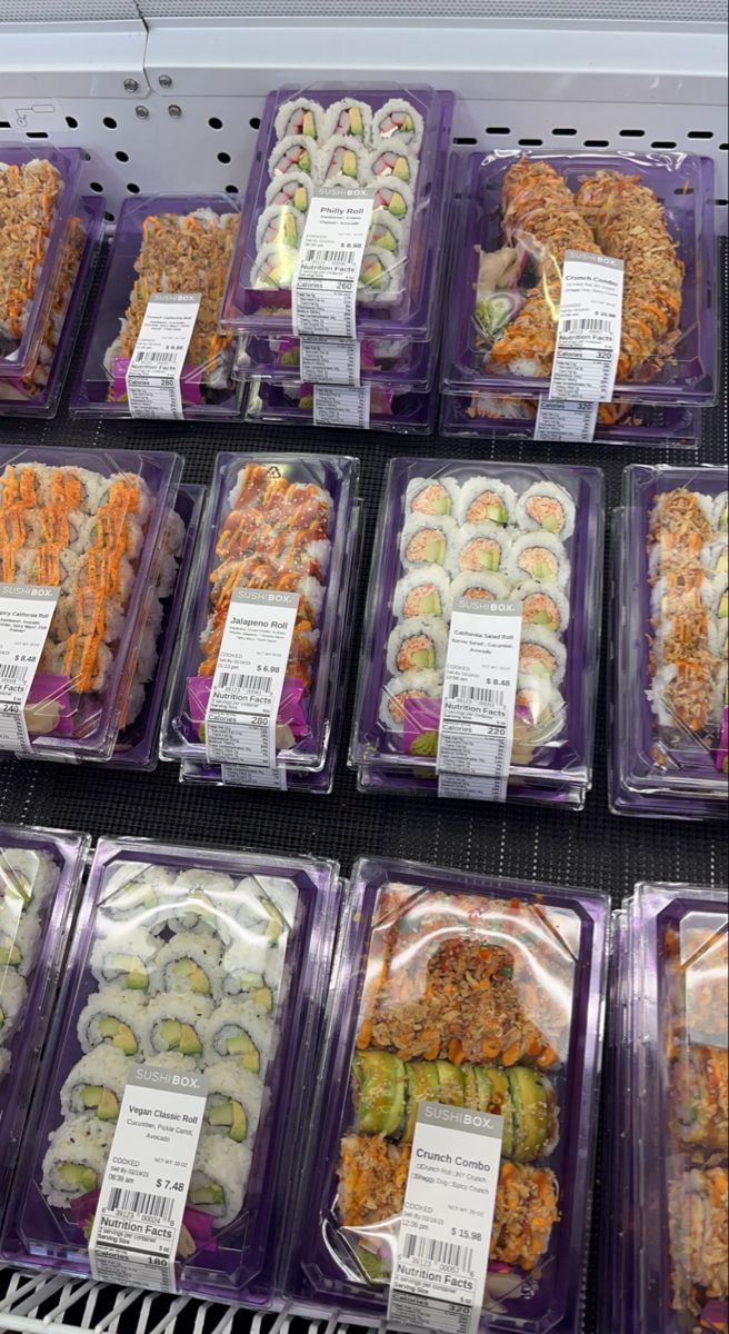 plastic trays filled with different types of sushi and other foods on display in a store