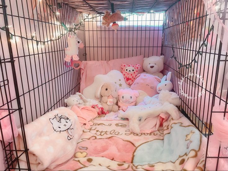 a cage filled with stuffed animals in pink and white blankets on top of a bed