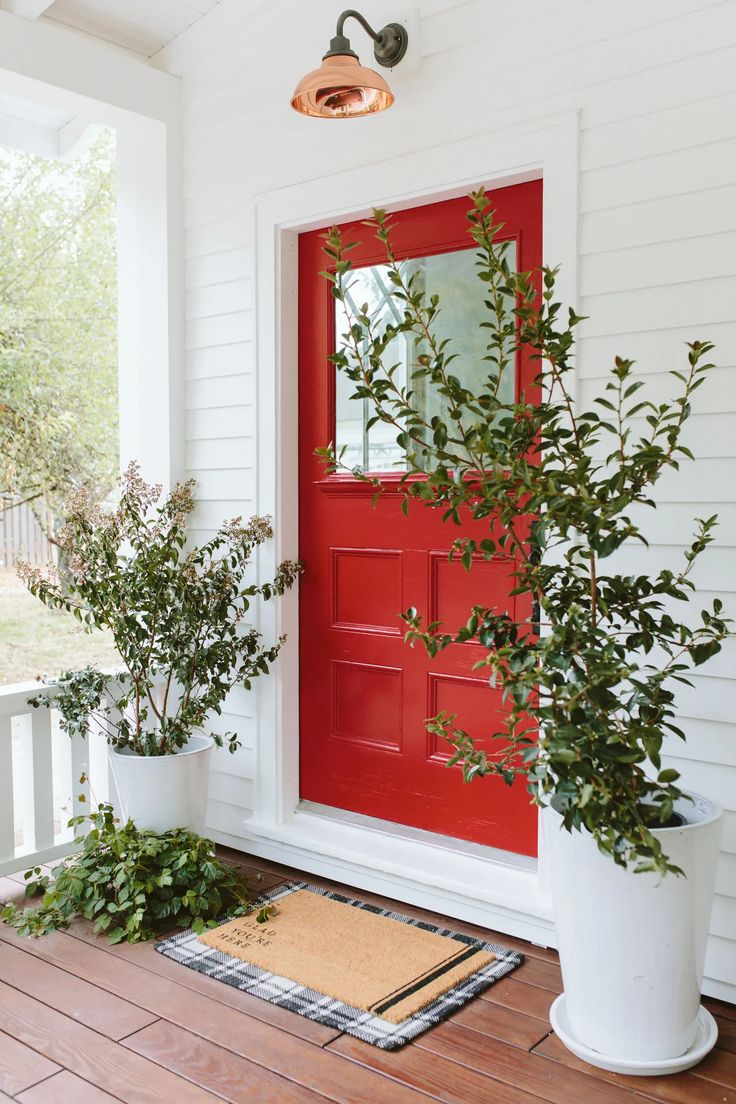 a red door and some plants on the porch