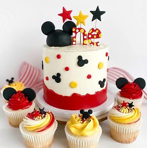 a mickey mouse birthday cake surrounded by cupcakes