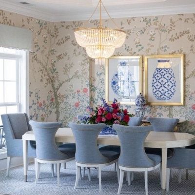 a formal dining room with blue chairs and floral wallpaper on the walls, along with a chandelier