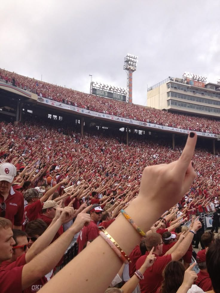 a crowd of people at a stadium with their hands in the air and one hand up