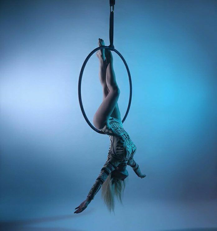 a woman is doing aerial acrobatics on a hoop