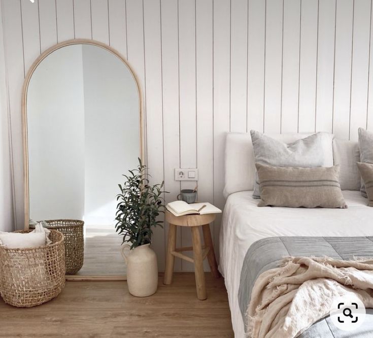 a bedroom with a bed, mirror and basket on the floor in front of it