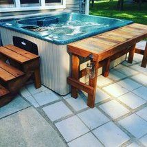 a hot tub sitting on top of a patio next to a picnic table and benches