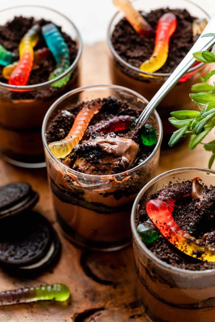 three desserts with chocolate and candy in them on a wooden table next to oreos