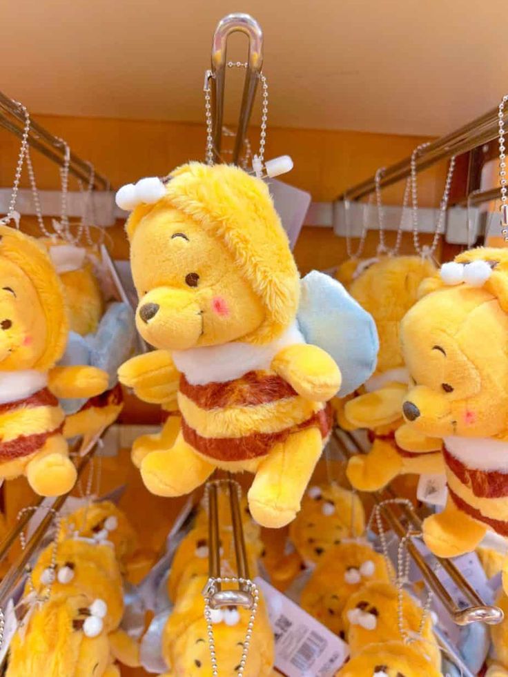 winnie the pooh keychains are hanging from hooks in a store with other winnie the pooh stuffed animals