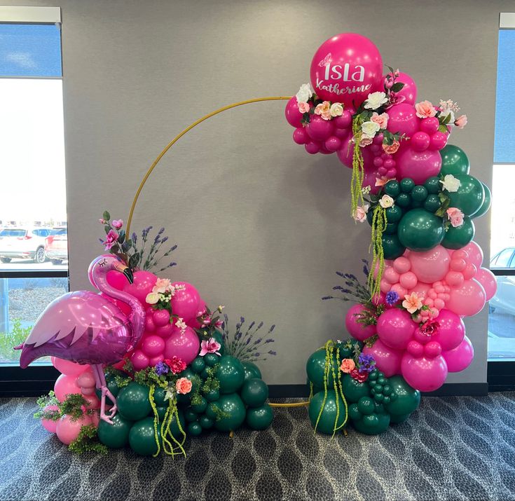 the balloon arch is decorated with flamingos and flowers