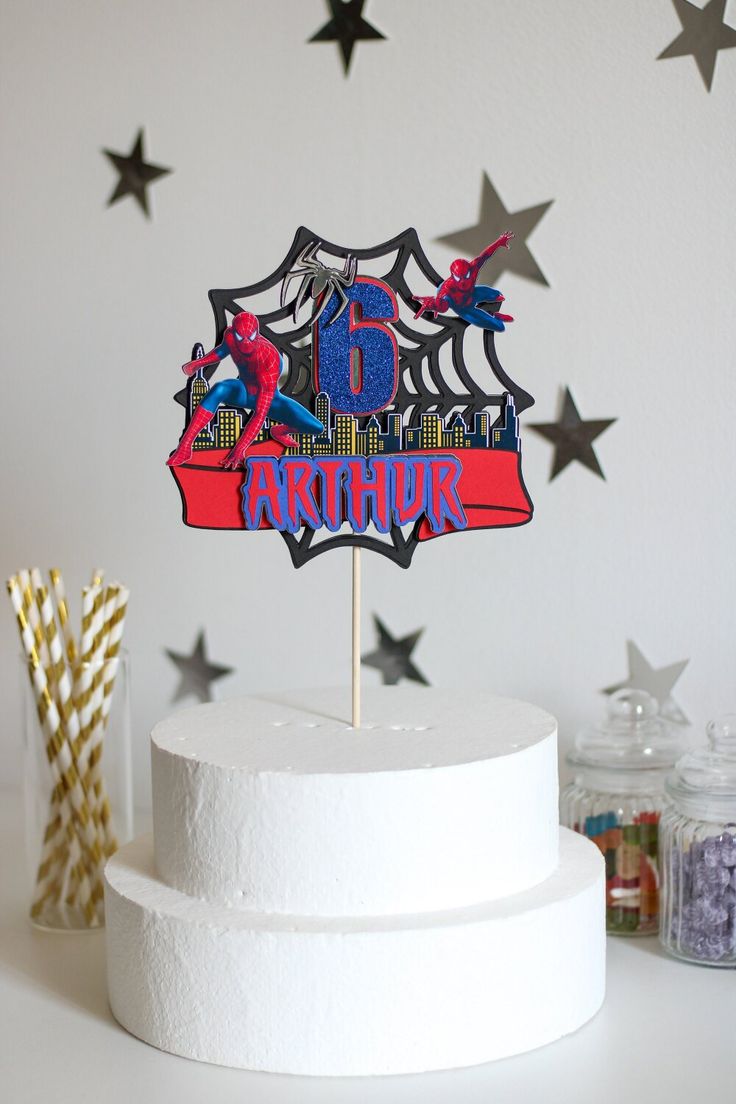 a spiderman cake topper sitting on top of a white cake