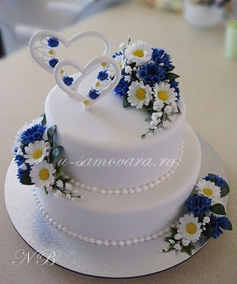 a wedding cake decorated with daisies and blue flowers